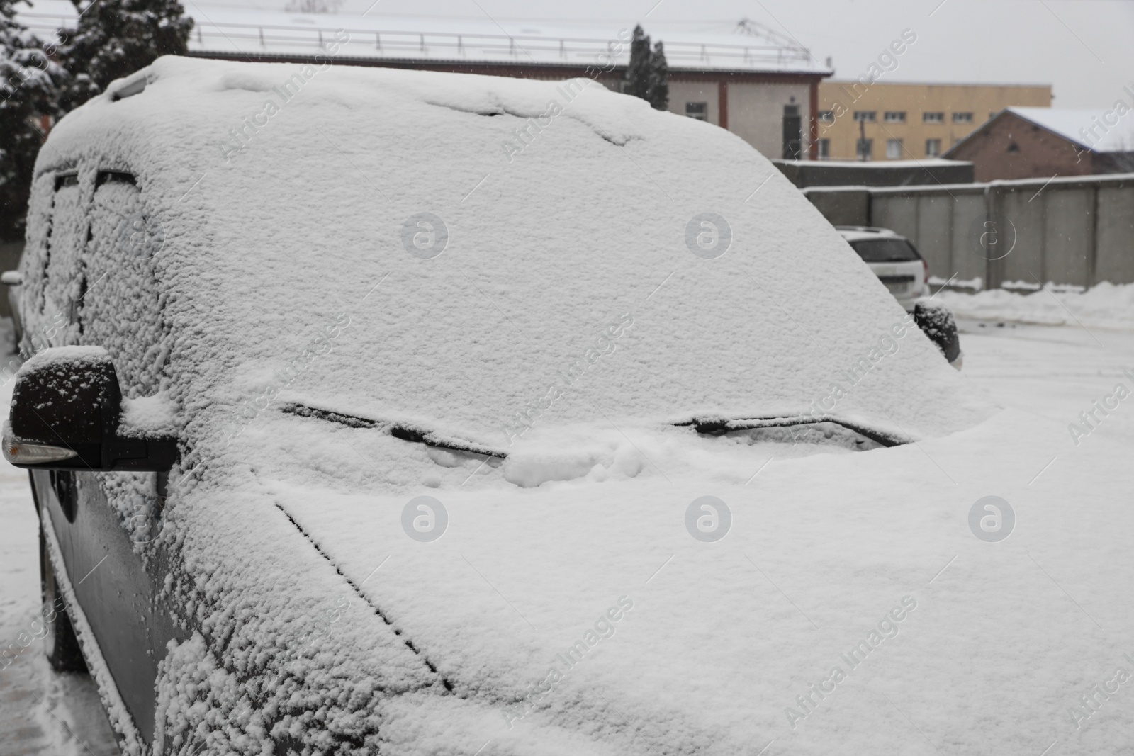 Photo of Car with windscreen wipers covered with snow outdoors on winter day