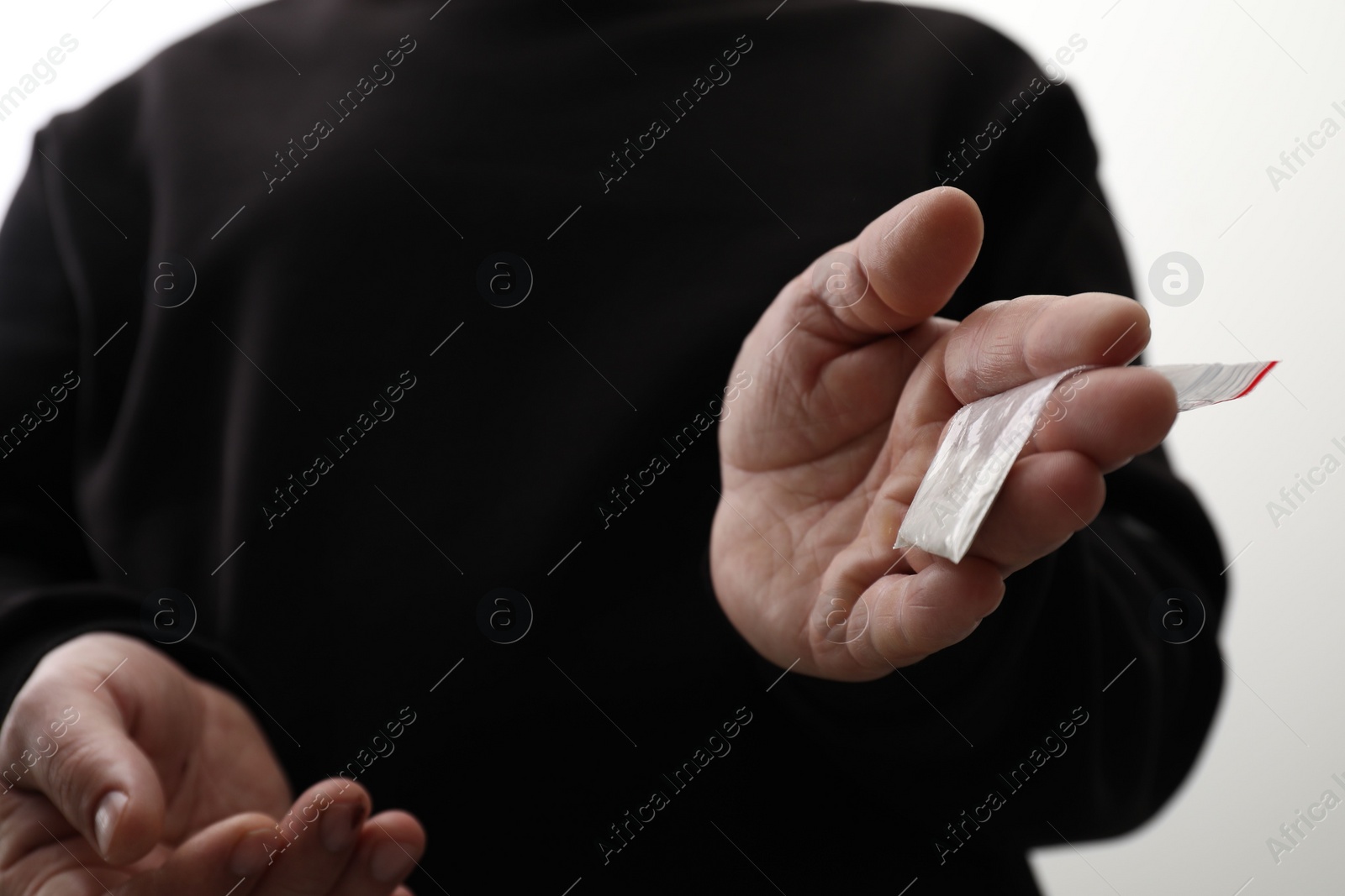 Photo of Drug addiction. Man with plastic bag of cocaine on light background, closeup