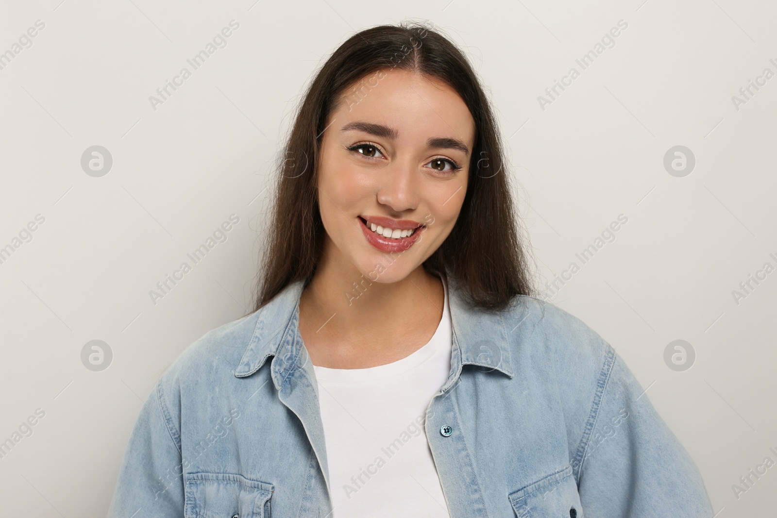 Photo of Portrait of happy young woman in jeans jacket on white background