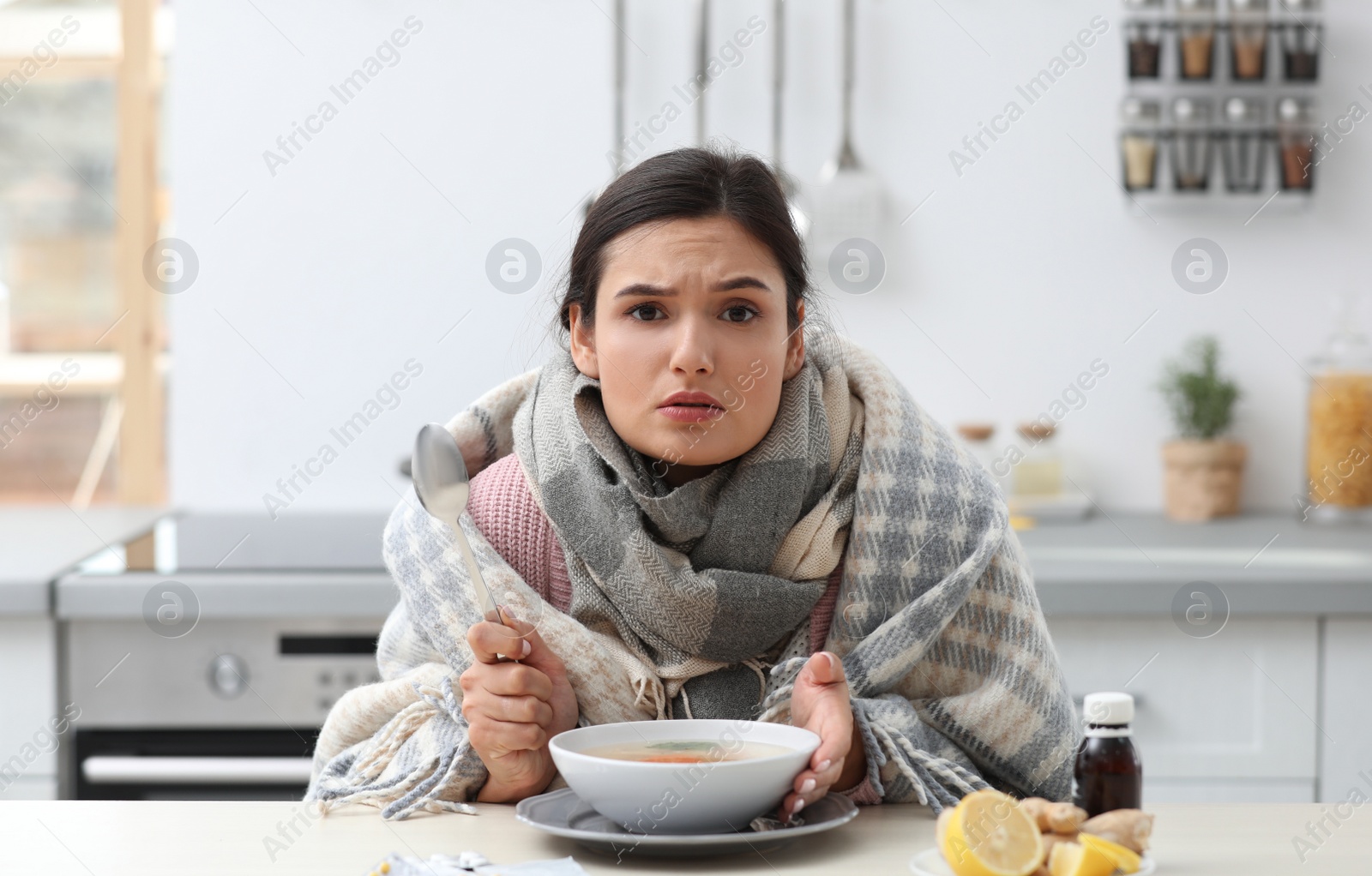 Photo of Sick young woman eating soup to cure flu at table in kitchen
