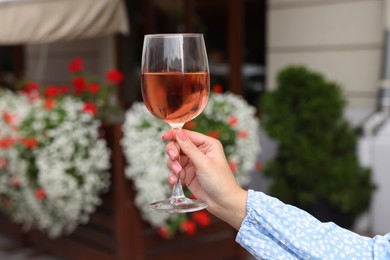 Photo of Woman holding glass of rose wine outdoors, closeup