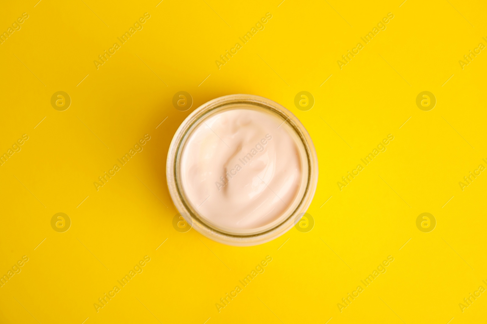 Photo of Tasty organic yogurt on yellow background, top view