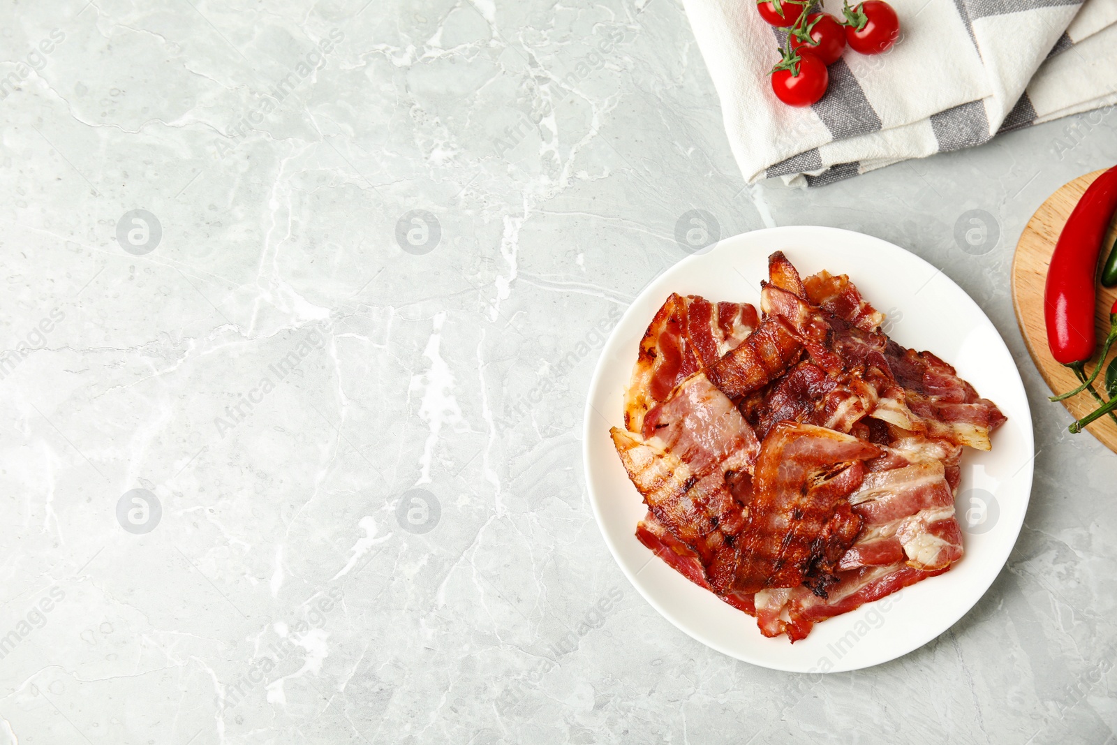 Photo of Slices of tasty fried bacon on light marble table, flat lay. Space for text