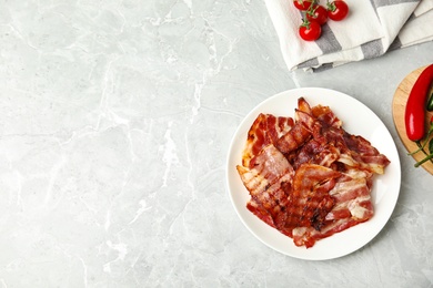 Photo of Slices of tasty fried bacon on light marble table, flat lay. Space for text