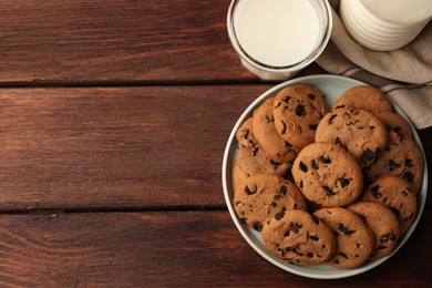 Photo of Delicious chocolate chip cookies and milk on wooden table, flat lay. Space for text