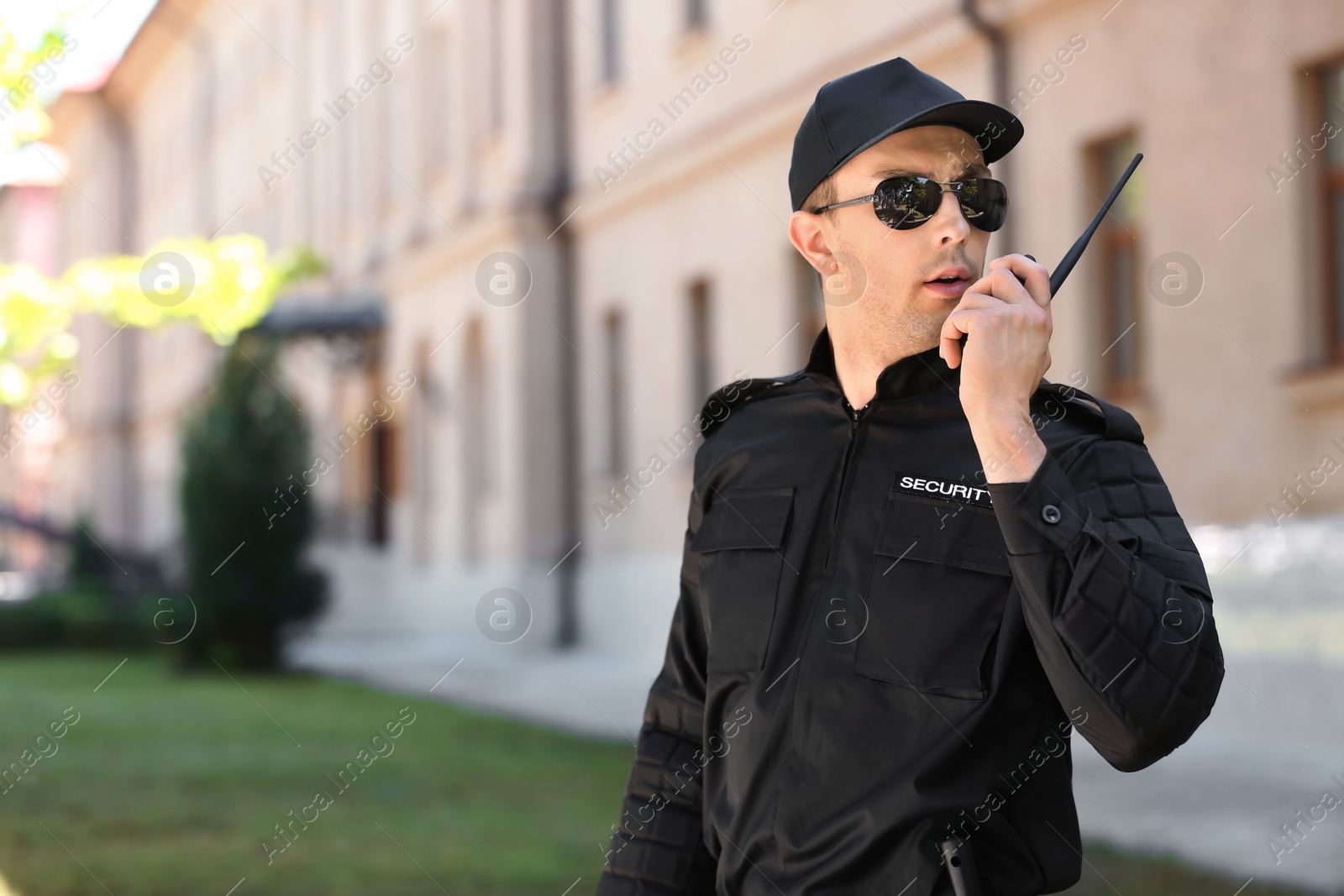 Photo of Male security guard using portable radio transmitter outdoors