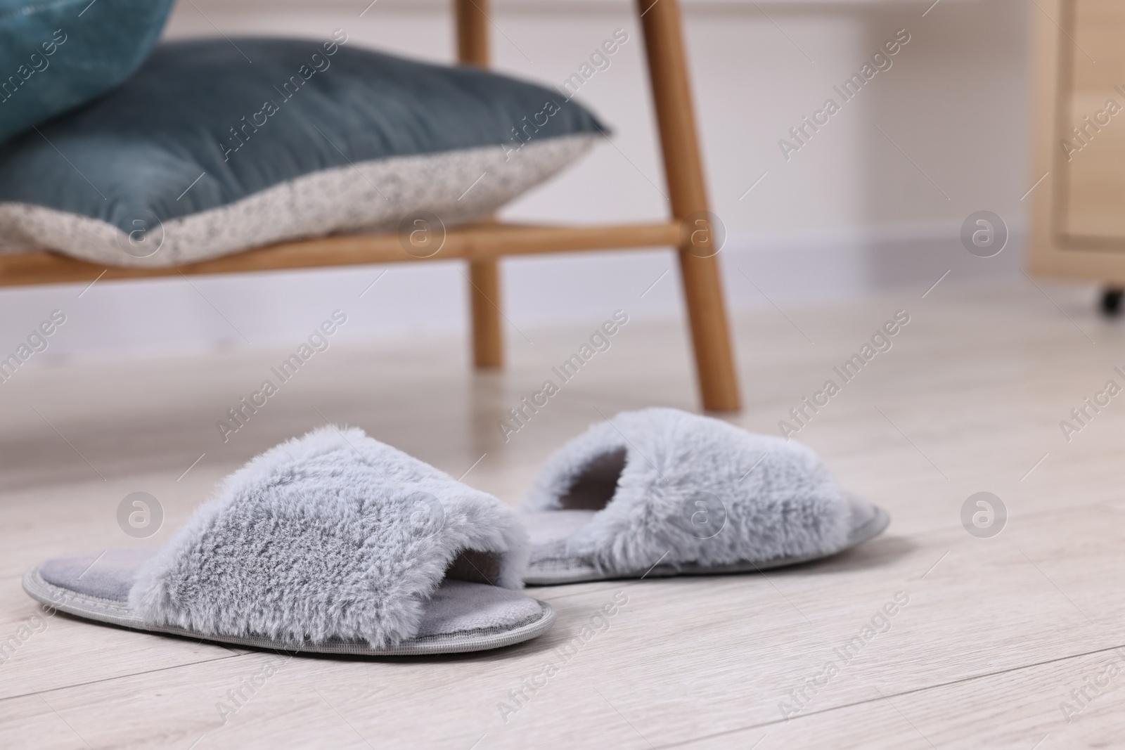 Photo of Grey soft slippers on light wooden floor indoors, closeup