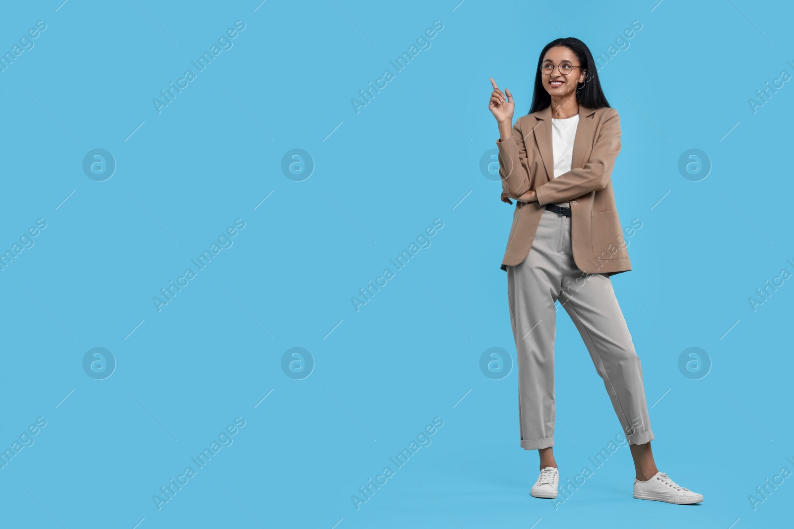 Photo of Beautiful secretary pointing at something on light blue background, space for text