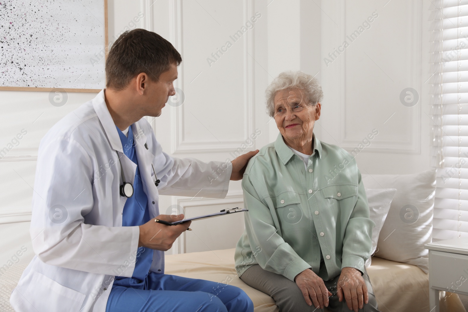 Photo of Caregiver examining senior woman in room. Home health care service