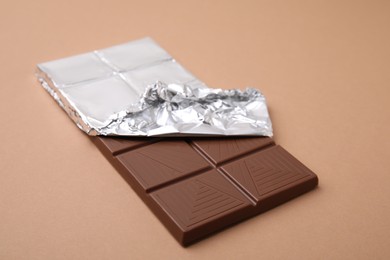 Photo of One tasty chocolate bar on brown background