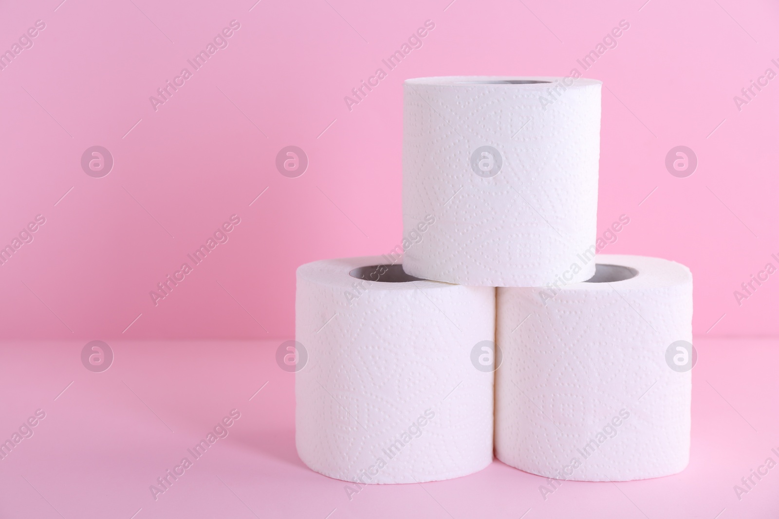 Photo of Soft toilet paper rolls on pink background, closeup. Space for text