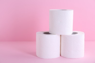 Photo of Soft toilet paper rolls on pink background, closeup. Space for text