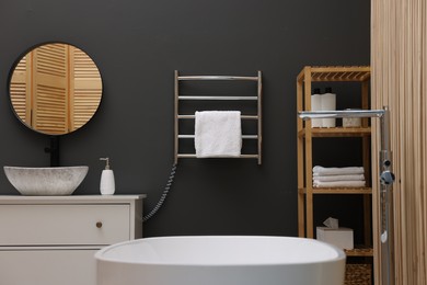 Stylish bathroom interior with heated towel rail and white tub