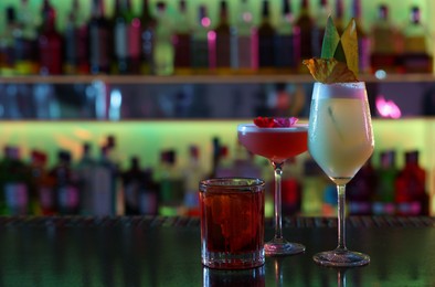 Photo of Different fresh alcoholic cocktails on counter in bar. Space for text