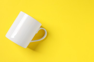 Photo of One white ceramic mug on yellow background, top view space for text