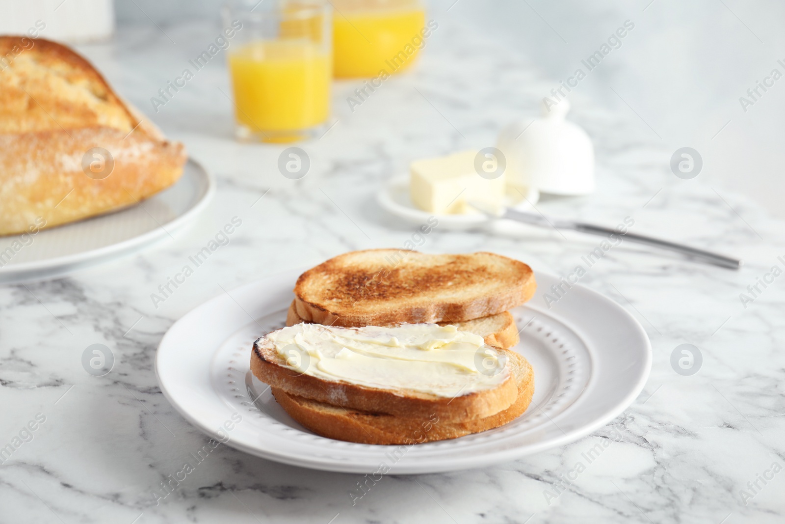 Photo of Tasty bread with butter served for breakfast on marble table