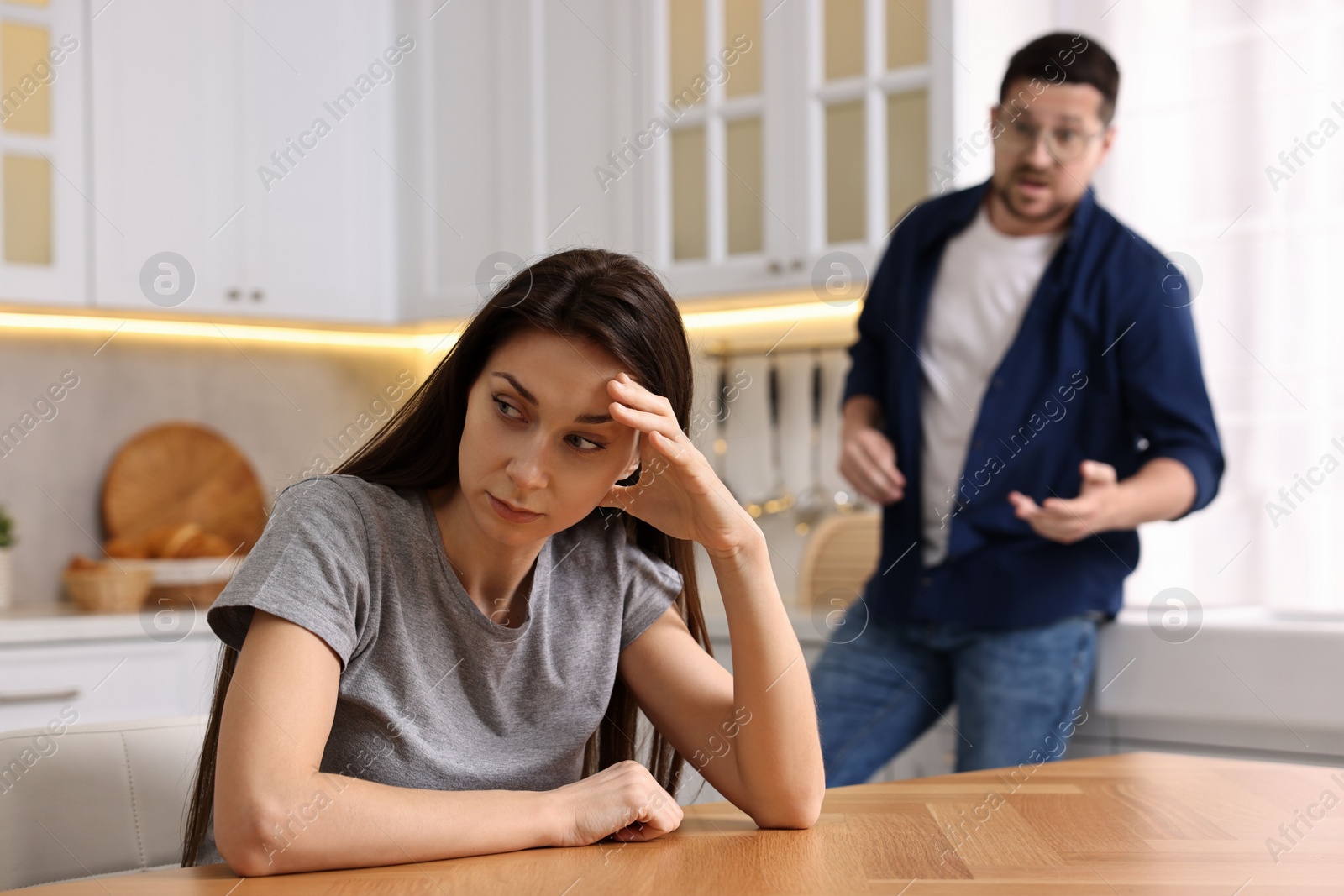 Photo of Stressed wife trying to ignore her angry husband in kitchen, selective focus. Relationship problems