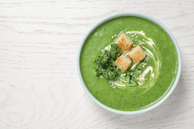 Photo of Tasty kale soup on white wooden table, top view. Space for text