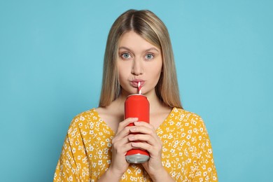 Photo of Beautiful woman drinking from red beverage can on light blue background