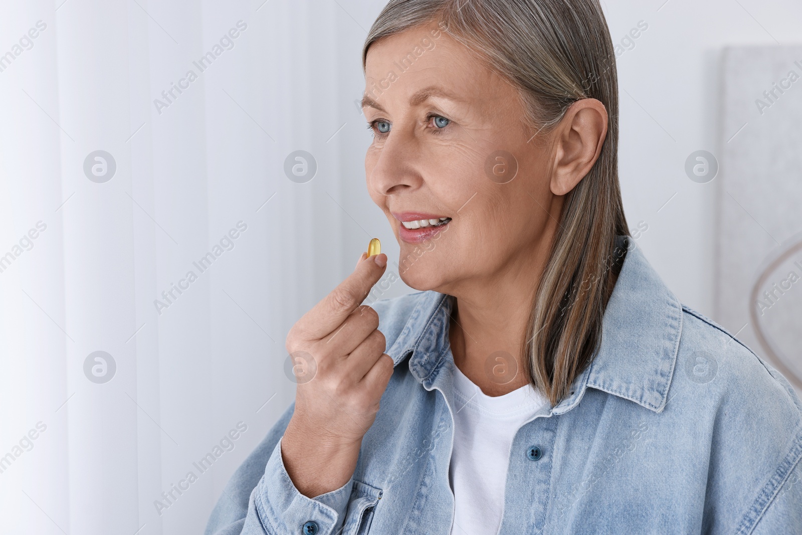 Photo of Beautiful woman taking vitamin pill at home