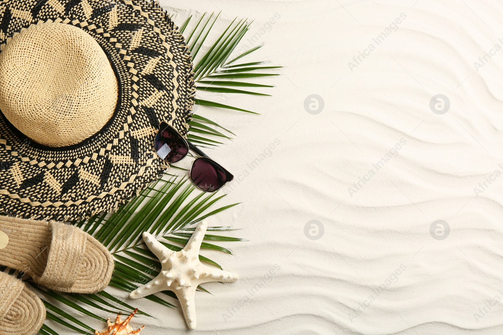 Photo of Different beach accessories on sand, flat lay. Space for text