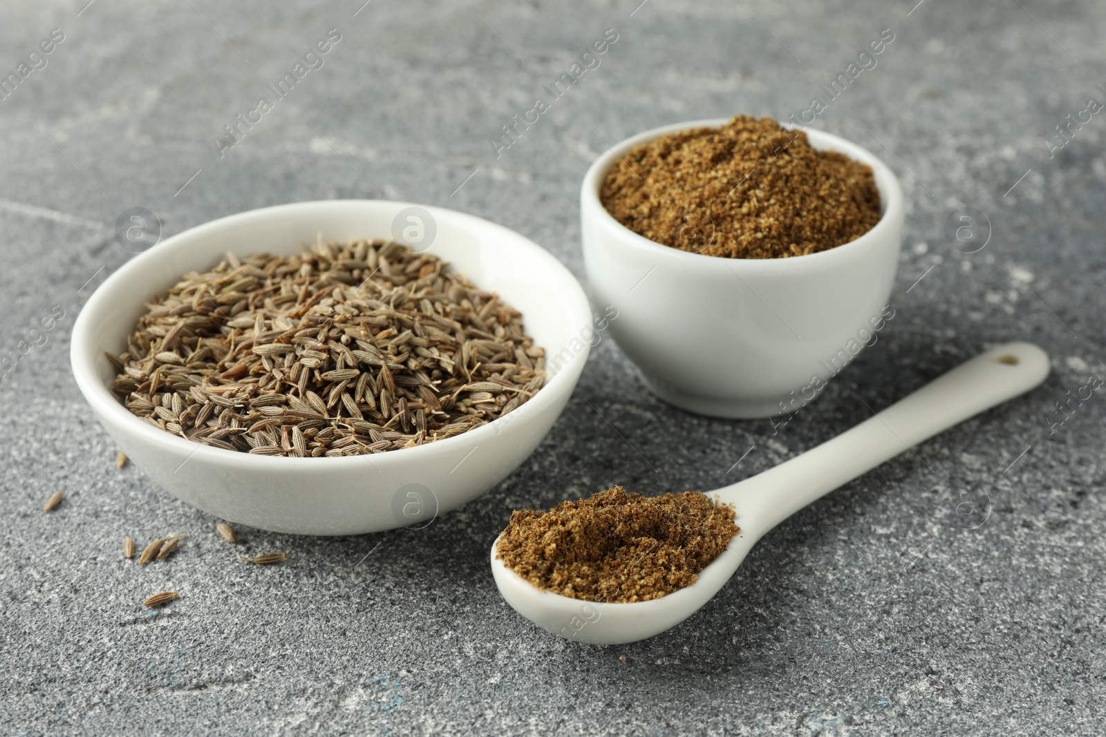 Photo of Caraway (Persian cumin) seeds and powder on light gray textured table