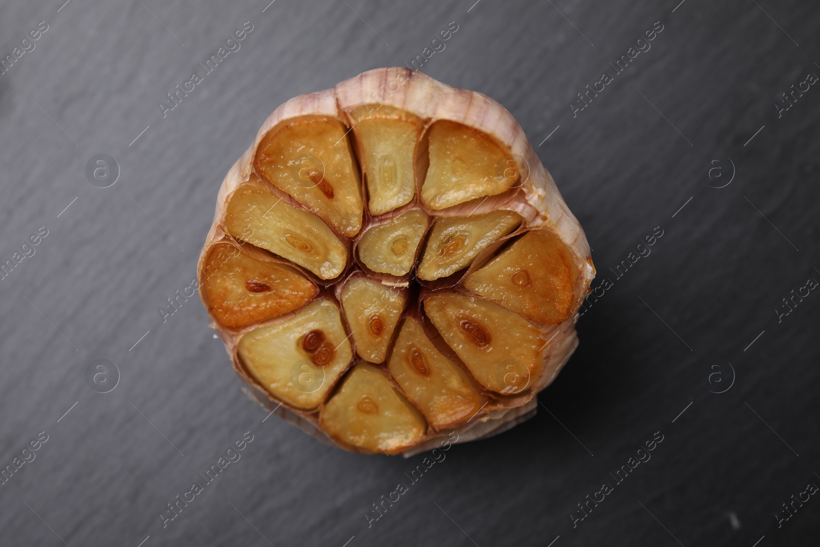 Photo of Head of fried garlic on dark gray table, closeup