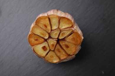Photo of Head of fried garlic on dark gray table, closeup