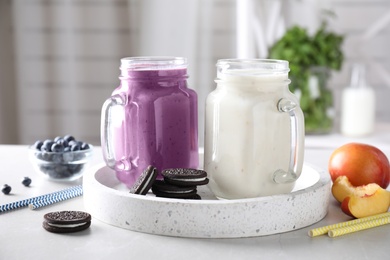 Photo of Tasty milk shakes in mason jars on tray