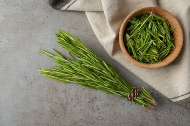 Photo of Bowl with fresh rosemary twigs on grey background, flat lay