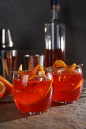 Photo of Aperol spritz cocktail, ice cubes and orange slices in glasses on grey textured table