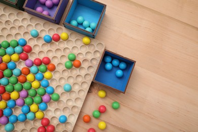 Photo of Wooden sorting board and boxes with colorful balls on table, flat lay. Montessori toy