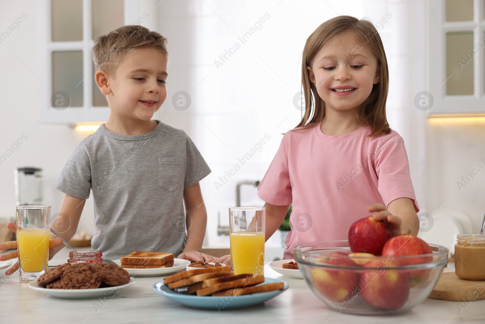 Photo of Little children having breakfast at table in kitchen