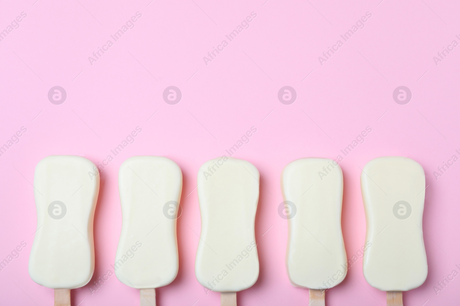 Photo of Glazed ice cream bars on pink background, flat lay. Space for text