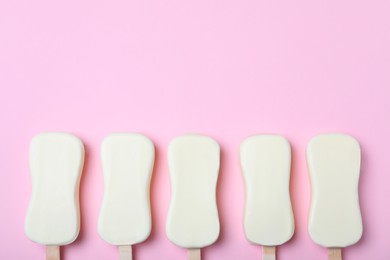 Glazed ice cream bars on pink background, flat lay. Space for text