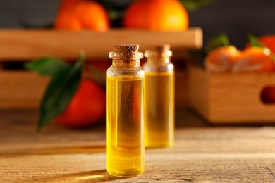 Bottles of tangerine essential oil on wooden table, closeup