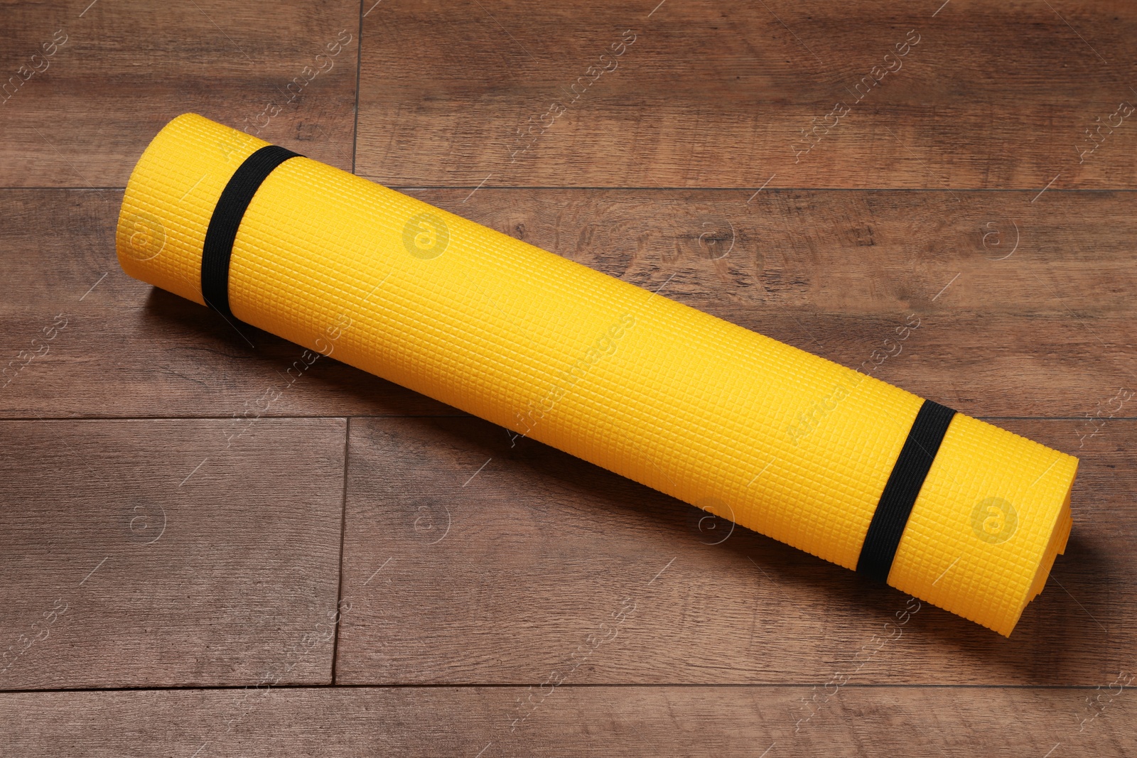 Photo of Bright rolled camping mat on wooden background