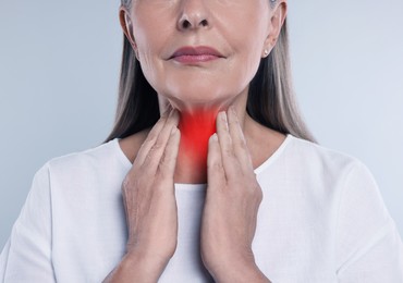 Endocrine system. Woman doing thyroid self examination on grey background, closeup