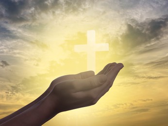 Image of Religion. Christian woman praying against sky with glowing cross, closeup