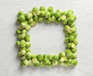 Photo of Frame made with Brussels sprouts on wooden background, top view. Space for text