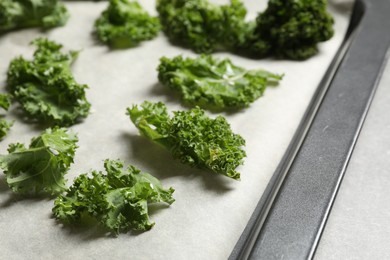 Photo of Raw cabbage leaves on baking sheet, closeup. Preparing kale chips