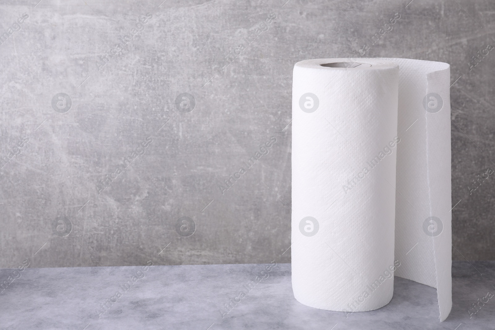 Photo of One roll of paper towels on grey table, space for text