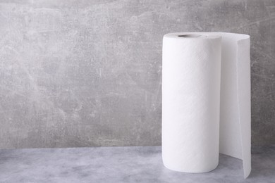 Photo of One roll of paper towels on grey table, space for text