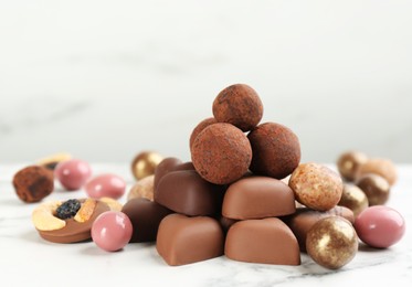 Different delicious chocolate candies on white marble table