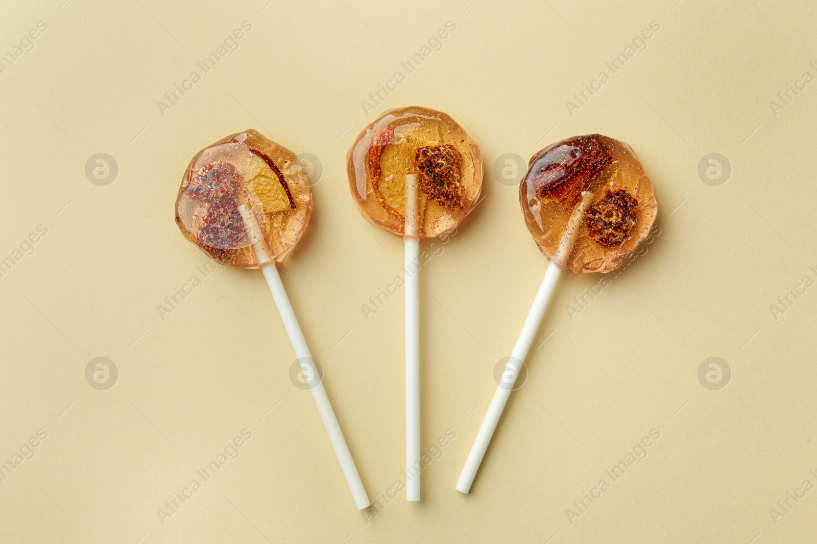 Photo of Sweet colorful lollipops with berries on beige background, flat lay