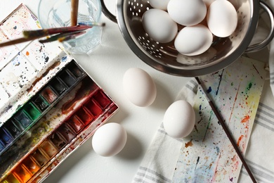Photo of Painting Easter eggs on white table, flat lay