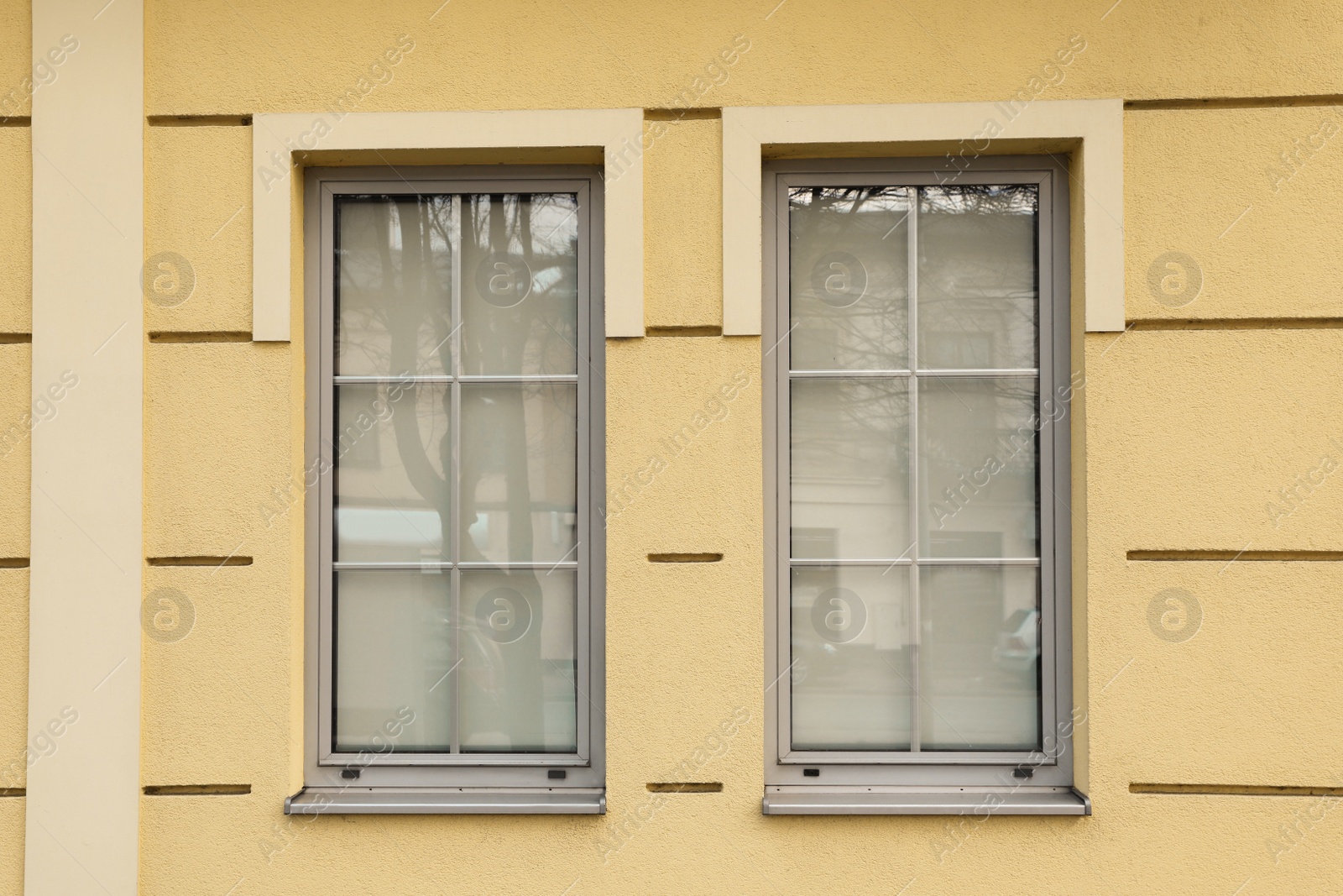 Photo of Yellow wall of building with stylish grey windows