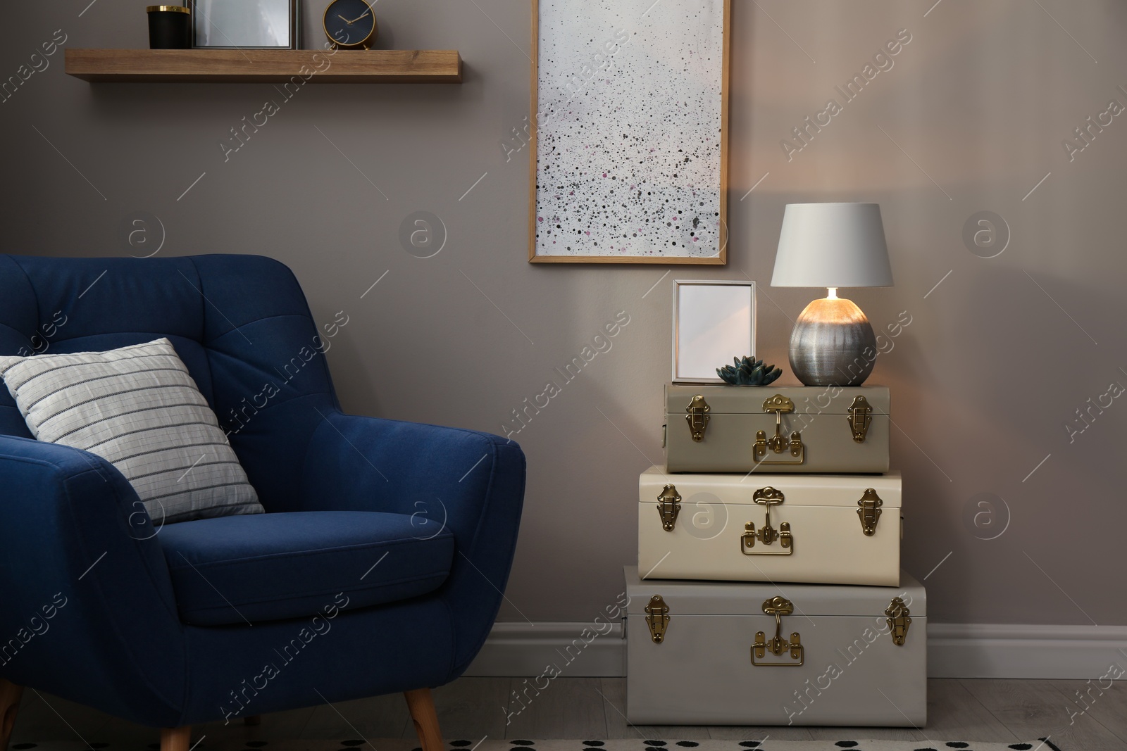 Photo of Stylish room interior with comfortable armchair and storage trunks near grey wall