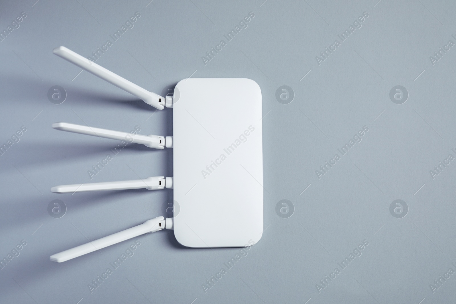 Photo of New stylish Wi-Fi router on grey background, top view. Space for text
