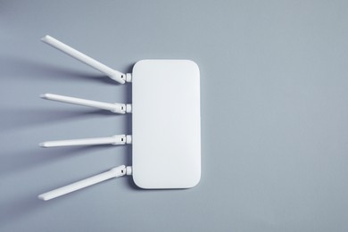 Photo of New stylish Wi-Fi router on grey background, top view. Space for text